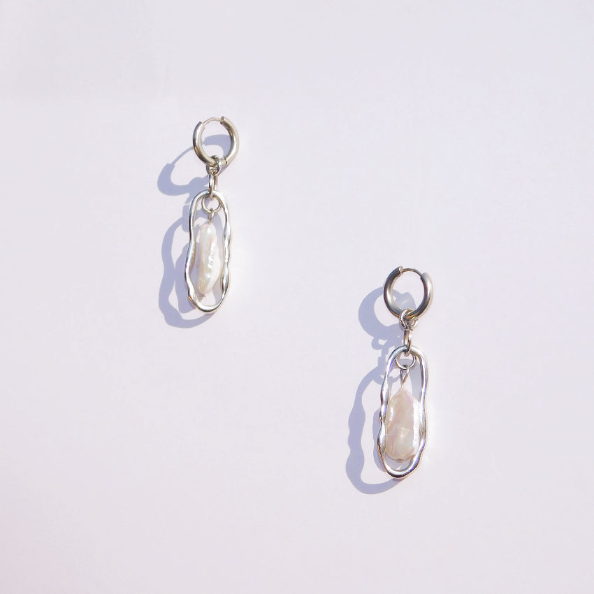 Pair of stainless steel silver colour earrings with a central Keshi Freshwater Pearl  on a white background